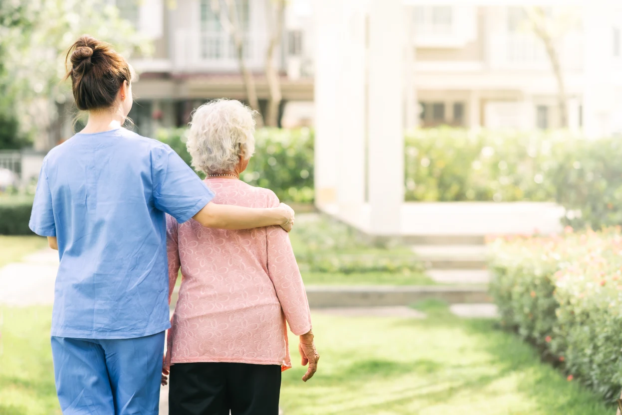 Carer supporting an elderly lady on a walk