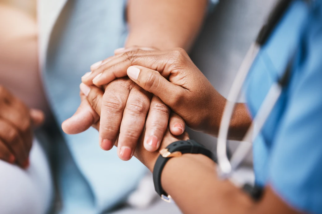 Nurse gently holding a patient's hands