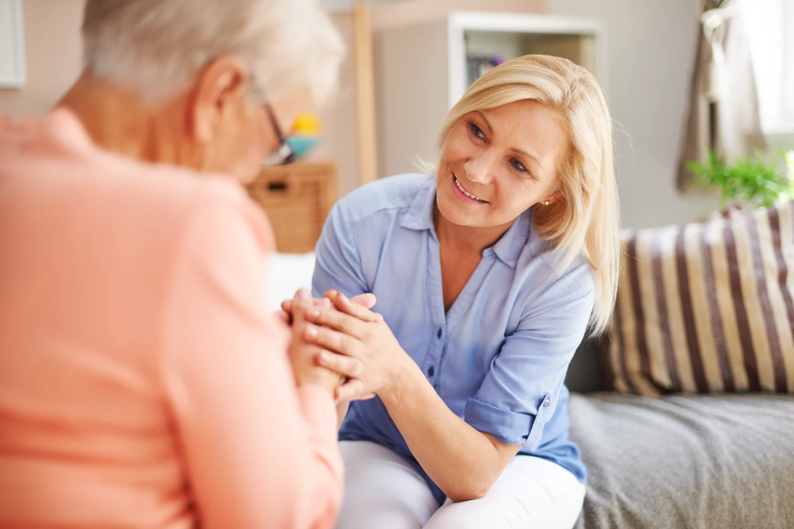 Carer smiling warmly with an elderly woman at home